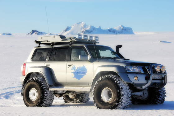 Sølvgrå super jeep med IceTour-logo på døra parkert på snødekt isbre